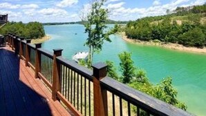 Een houten terras met uitzicht op een turquoise meer onder een heldere lucht.