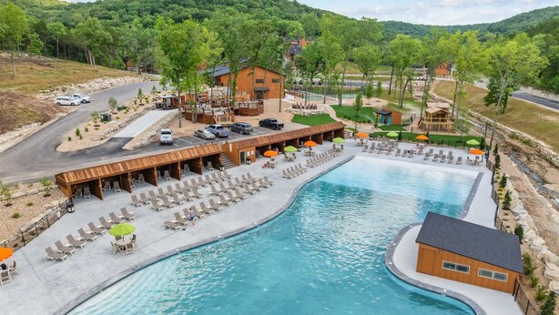 Um resort com uma piscina grande, área de estar externa e vista para as colinas ao redor.