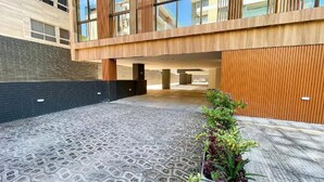Un edificio moderno con patio empedrado, fachada de madera y planta en maceta.