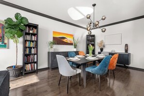 Ein Essbereich mit einem Tisch für vier Personen, umgeben von Stühlen, einem Bücherregal und einem Bild an der Wand.
