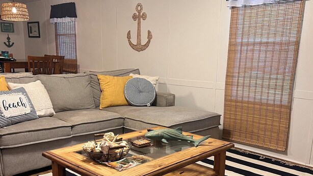 Ein Wohnzimmer mit einer Couch, einem Holztisch, gestreiften Teppichen und einer Wanddekoration.