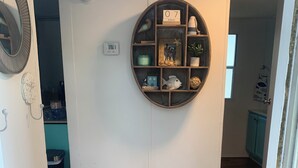 Ein Flur mit Holzboden, einer runden Wanddekoration, einer Tür mit Kalender und einem kleinen Fenster.
