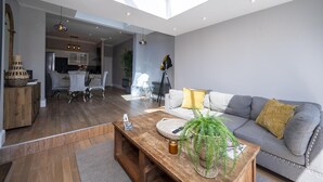 Ein modernes Wohnzimmer mit Sofa, Couchtisch und einem Essbereich mit Stühlen und Tisch.
