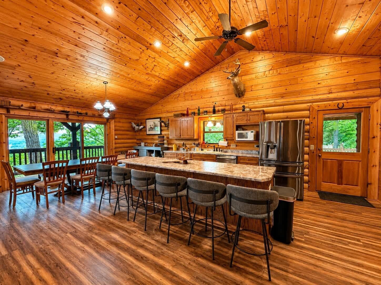 A log cabin interior with a kitchen, dining area, and bar stools.