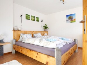 A bedroom with a wooden bed, a bedside table, a lamp, and a wall-mounted plant. - Chasa Aglia, (Ftan) by Interhome (Ftan)
