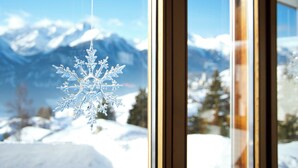 A snowflake ornament hanging by a window with a view of snow-covered mountains. - Chasa Aglia, (Ftan) by Interhome (Ftan)