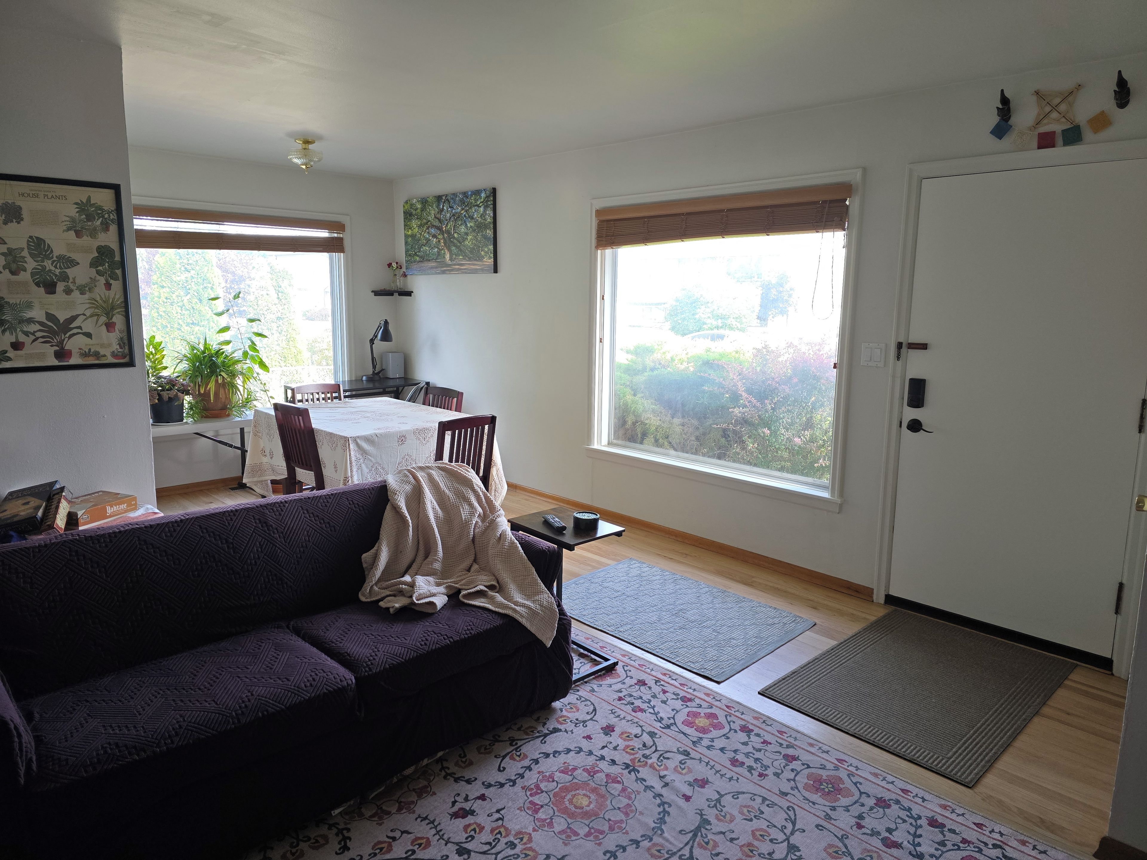Ein Wohnzimmer mit einer Couch, einem Esstisch und einem großen Fenster.