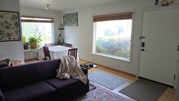 A living room with a sofa, a dining table, and a large window.