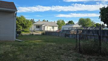 A residential area with a house, a fenced yard, and a clear sky.