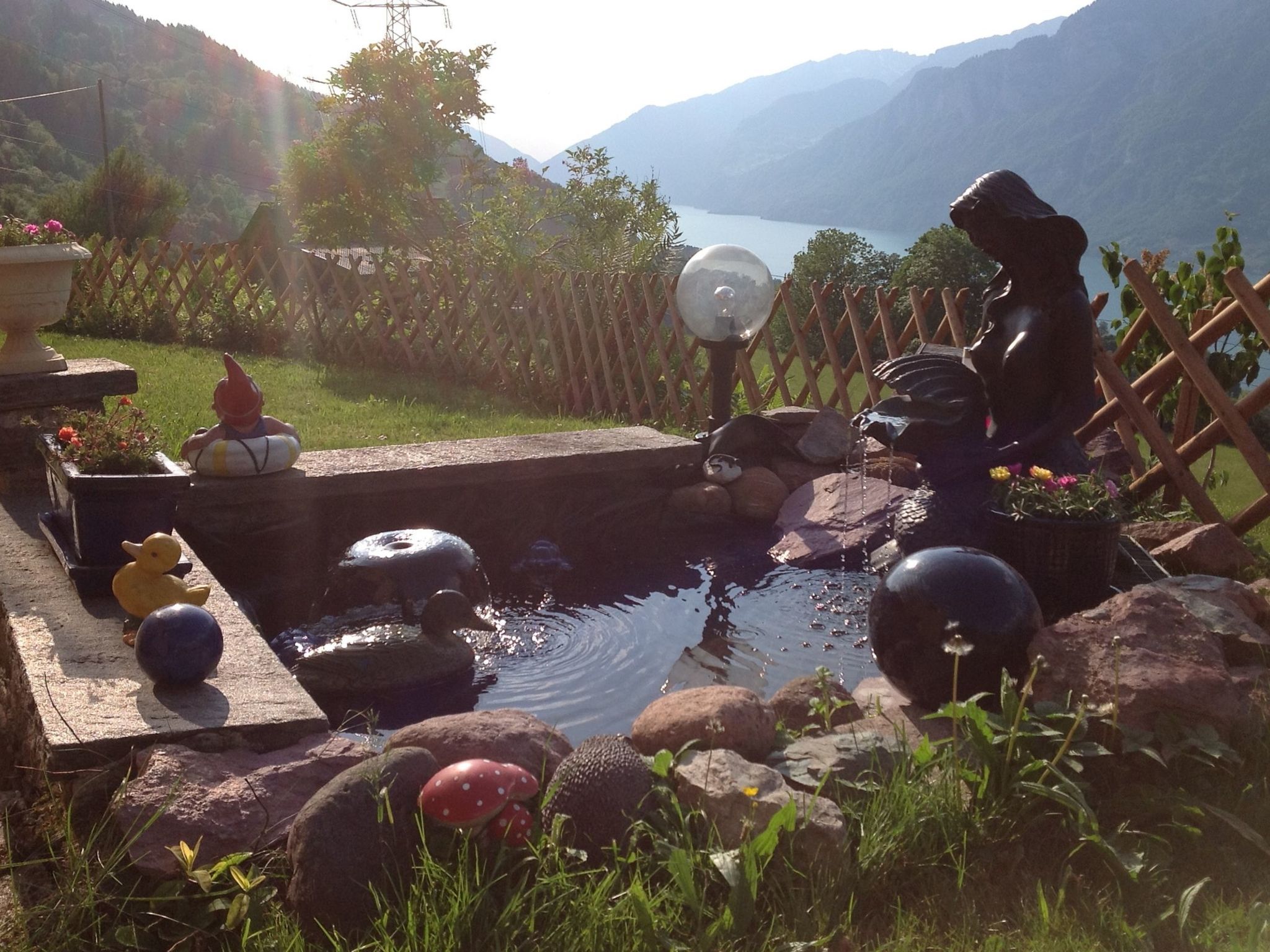 Un jardin avec un étang, des rochers décoratifs, un gnome et un canard.