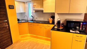 A compact kitchen with yellow cabinets, a black countertop, and a microwave. - Bijouswiss - The Yellow House****, (Oberterzen), by Interhome (Oberterzen)