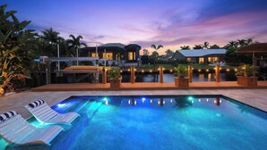 A swimming pool with lounge chairs, a covered deck, and a sunset sky. - Luxury Gulf-Access Retreat with Pool, Dock & Sunsets (Bonita Springs)