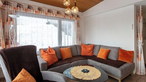 A living room with a sectional sofa, armchairs, a coffee table, and a wooden ceiling.