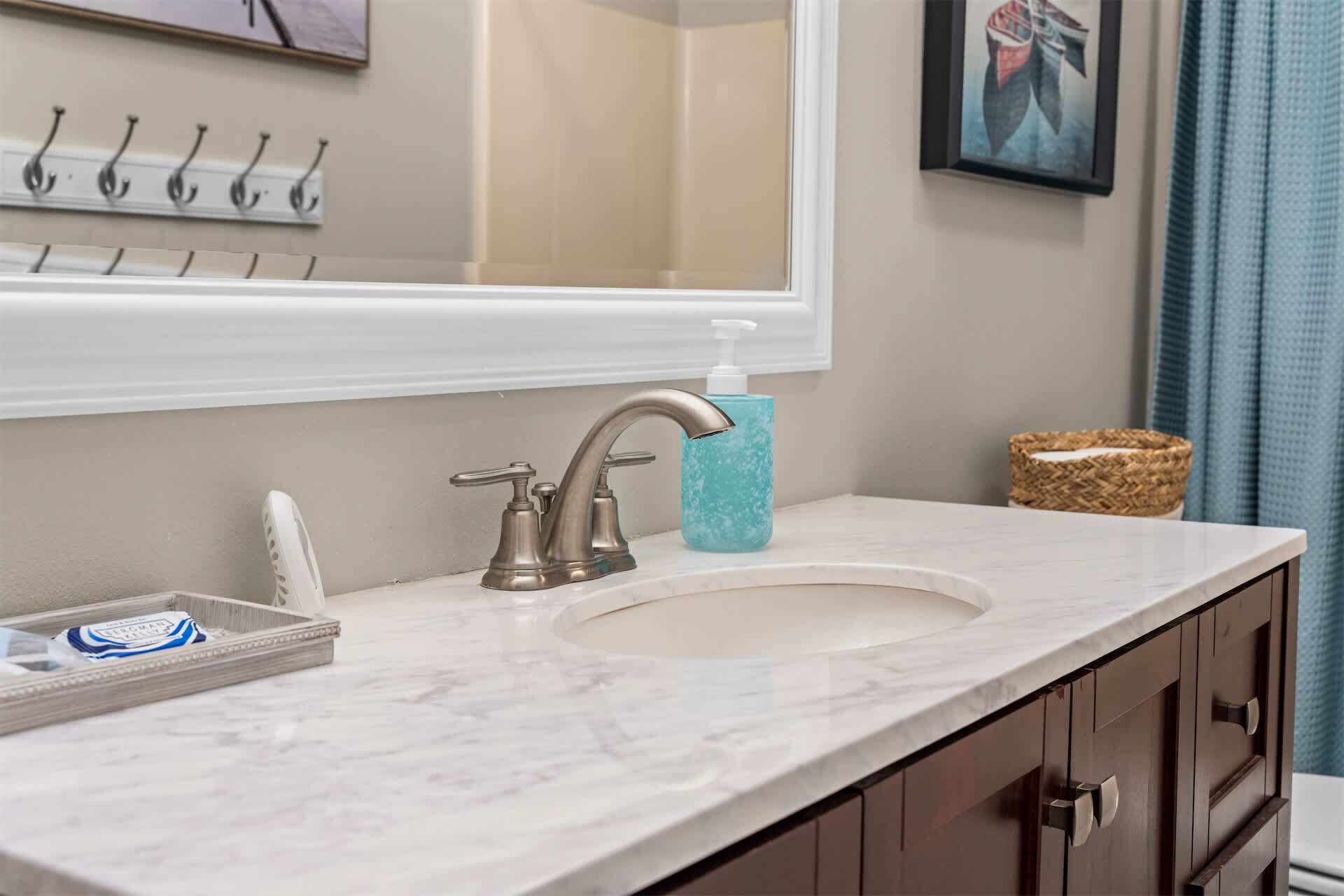 A bathroom with a marble sink, a faucet, a soap dispenser, and a towel rack.