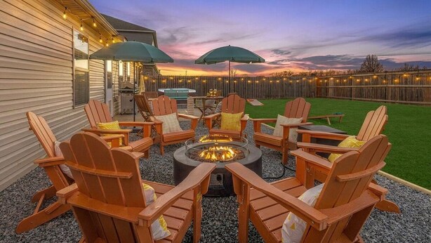 Un espace extérieur aménagé avec des chaises Adirondack, un foyer et des parasols.