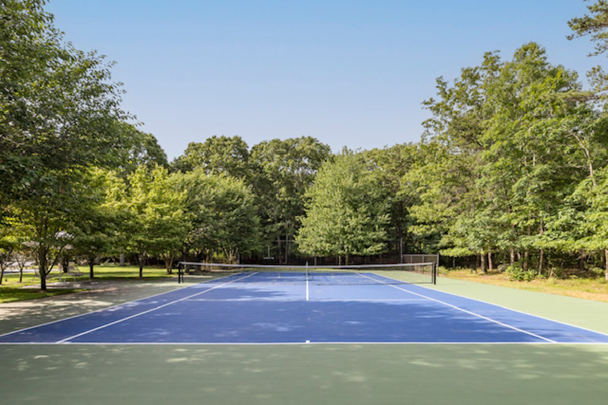 Un court de tennis entouré d’arbres.