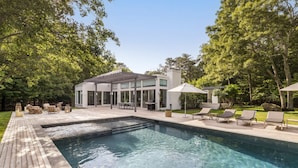 Una casa moderna con piscina, mobili da esterno e un'area patio.