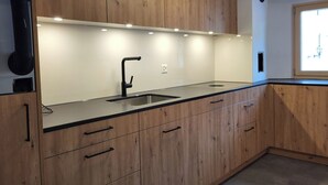 A modern kitchen with wooden cabinets, a black countertop, and a stainless steel sink. - La Rösa, (Sta. Maria Val Müstair) by Interhome (Sta. Maria GR)