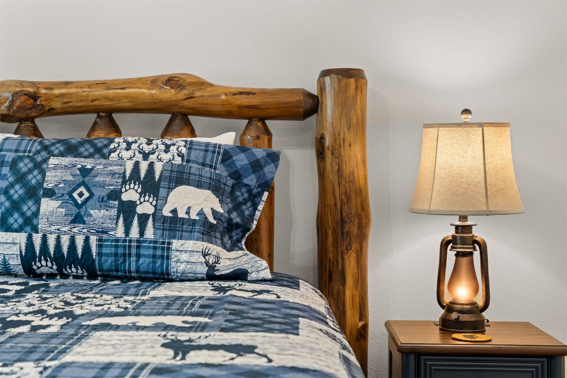 Un lit avec une couverture à motifs, une tête de lit en bois et une lampe de chevet.