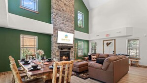 A spacious living area with a fireplace, a dining table set for four, and a comfortable sofa. - Lakesides Retreat With Amenities (Hollister)