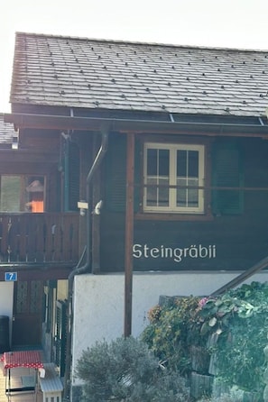 A traditional building with a dark wooden facade, a balcony, and a sign reading 'Steingräbii.' - Steingräbji 1. OG Süd Appartement/Fewo, Dusche oder Bad, WC by Interhome (Mörel-Breiten)