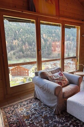 A room with a large window, a sofa, and a patterned rug.