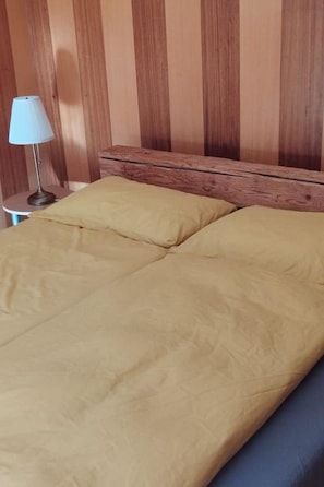 A bed with a wooden headboard and a lamp on a small table beside it. - Steingräbji 1. OG Süd Appartement/Fewo, Dusche oder Bad, WC by Interhome (Mörel-Breiten)