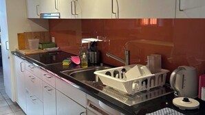 Eine moderne Küche mit weißen Schränken, einer schwarzen Arbeitsplatte und einem integriertem Geschirrspüler.
