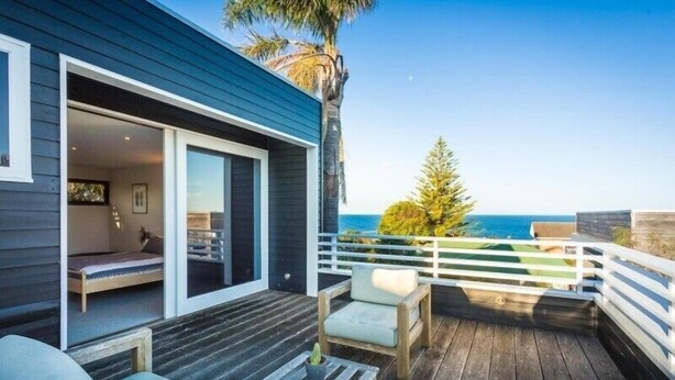A wooden deck with a bed, a sofa, and a small table. - East Lane (Bega Valley)
