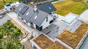 A modern house with a flat roof, large windows, and a garden area.