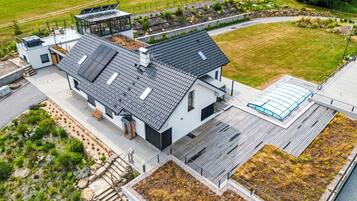 Une maison moderne avec un toit plat, de grandes fenêtres et un jardin.