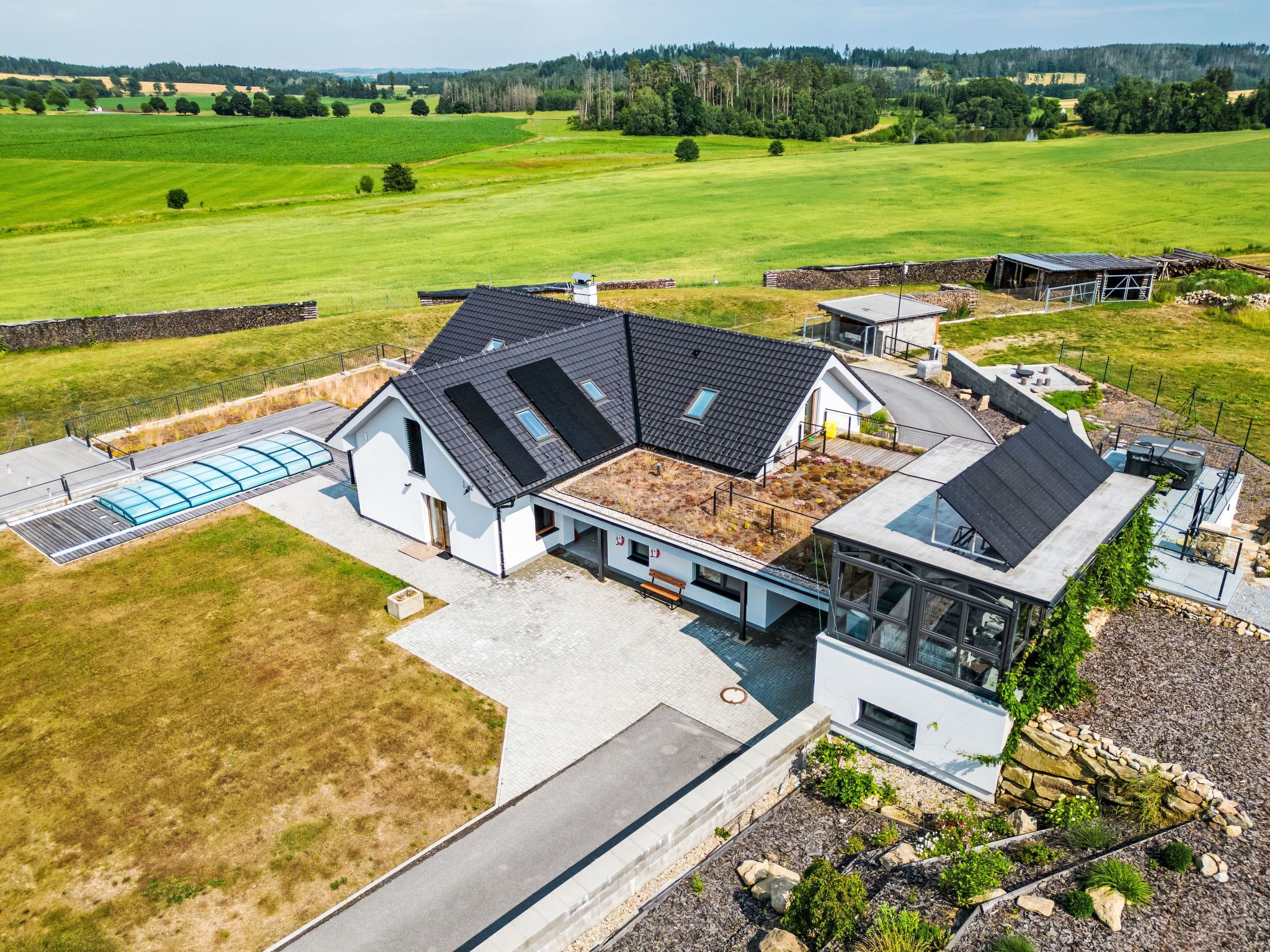 A modern house with a large glass conservatory, a sloped roof, and a view of a green field.