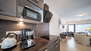 A modern kitchen with a built-in microwave, coffee machine, kettle, and a coffee cup on the counter.