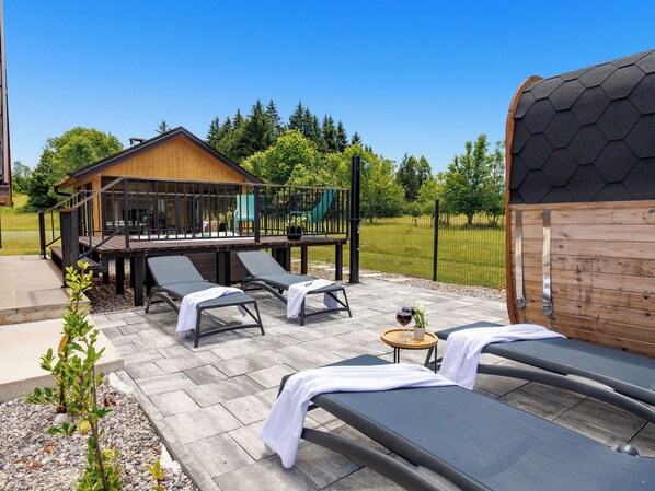 Eine Terrasse mit Liegestühlen, einem kleinen Tisch und einer Holzdeckfläche.