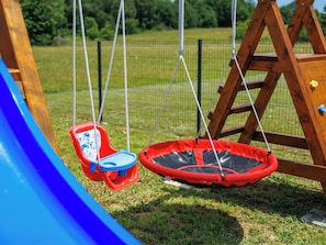 Ein Spielplatz mit Schaukel und Rutsche.