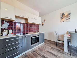 A modern kitchen with a marble backsplash, stainless steel appliances, and a dining area with a grey chair. - Apartment Vigi by Interhome (Pag/Povljana)