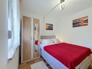 Ein Schlafzimmer mit einem Bett, einem Kleiderschrank, einem Spiegel und zwei Bildern an der Wand.