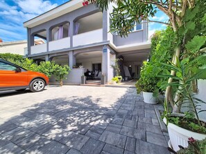 A two-story building with a covered entrance, potted plants, and a parked car. - Apartment Vigi by Interhome (Pag/Povljana)