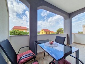 En balkon med et glasbord, to stole og udsigt til huse.