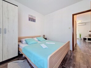 A bedroom with a bed, a wardrobe, a painting, and a hallway leading to a bathroom. - Apartment Vigi by Interhome (Pag/Povljana)