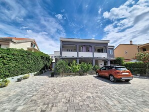 A two-story house with a paved driveway and a parked car. - Apartment Vigi by Interhome (Pag/Povljana)