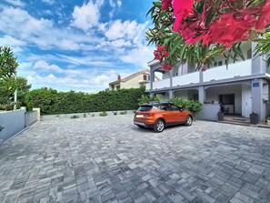 A paved driveway leading to a two-story building with a car parked in the driveway. - Apartment Vigi by Interhome (Pag/Povljana)