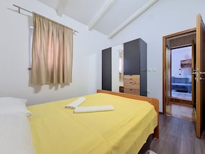 A bedroom with a bed, a mirror, a wooden wardrobe, and a door leading to another room. - Apartment Vigi by Interhome (Pag/Povljana)