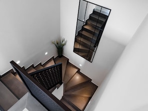 A modern staircase with a geometric design, a glass railing, and a potted plant. - Delight by Interhome (Krk/Dobrinj)