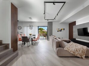 A modern living room with a sofa, TV, and staircase. - Delight by Interhome (Krk/Dobrinj)