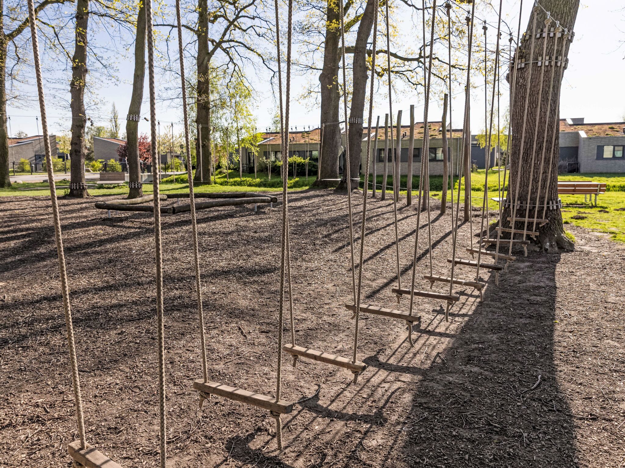 Ein Spielplatz mit Schaukeln und Sandkasten.