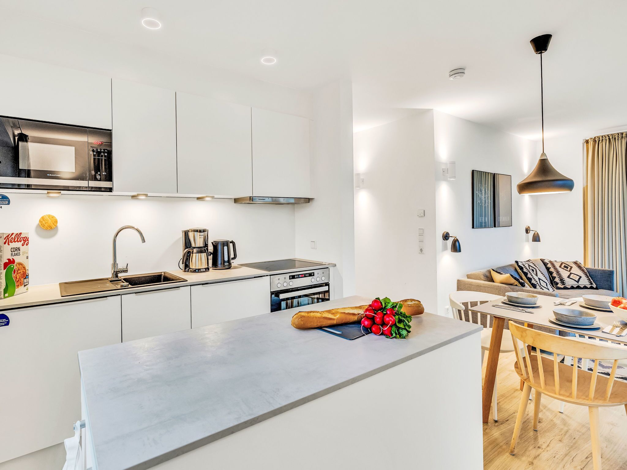Une cuisine moderne dotée d’un îlot central, d’appareils électroménagers intégrés et d’un coin repas avec une table et des chaises.
