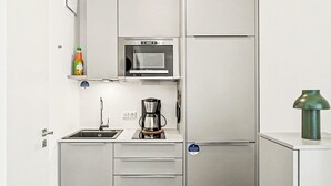 Et kompakt køkken med mikrobølgeovn, kaffemaskine og en skraldespand.
