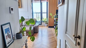 A hallway with a wooden herringbone floor, a sofa, a coffee table, and a potted plant. - Dzielna by Interhome (Warsaw)