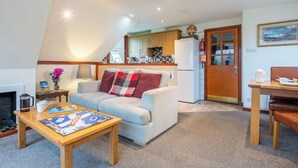 A cozy living room with a sofa, coffee table, and a dining area with a table and chairs. - Invergarry Combi by Interhome (Invergarry)